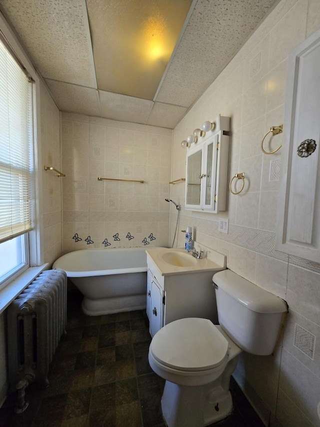 full bath featuring tile walls, radiator heating unit, a paneled ceiling, and a freestanding tub