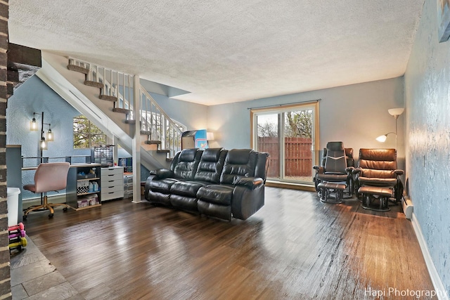 living area featuring stairway, a textured ceiling, a textured wall, and wood finished floors