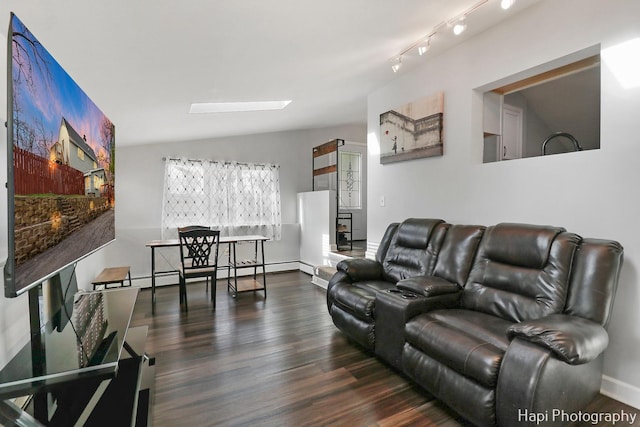 living area featuring baseboards, lofted ceiling with skylight, wood finished floors, and a baseboard heating unit