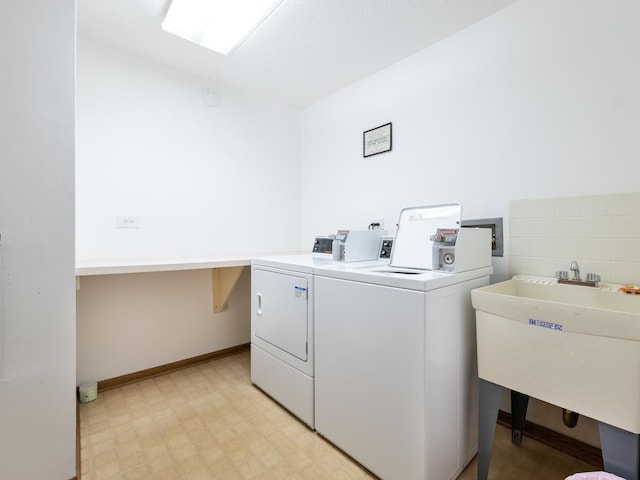 washroom featuring washer and dryer, baseboards, light floors, and a sink