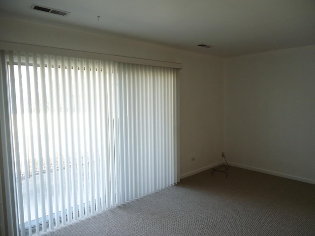 carpeted spare room featuring visible vents, plenty of natural light, and baseboards