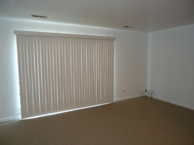 empty room with visible vents, baseboards, and carpet