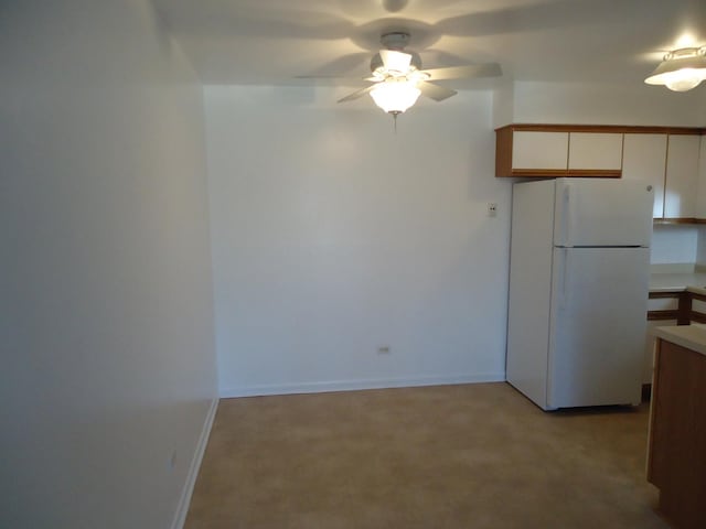 kitchen featuring a ceiling fan, white cabinetry, freestanding refrigerator, light countertops, and baseboards