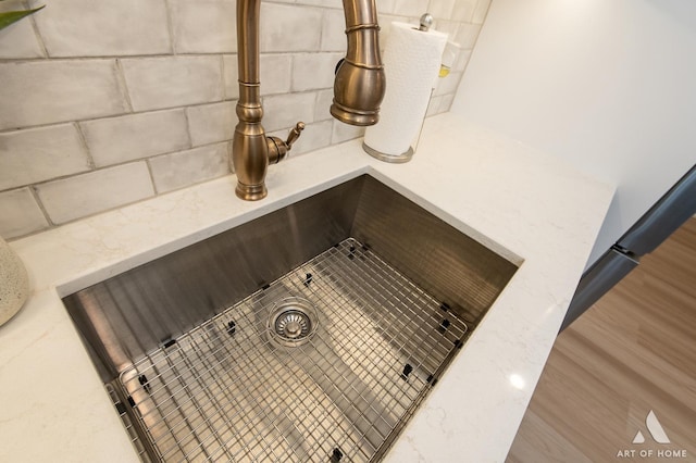 interior details with light stone counters, wood finished floors, and a sink