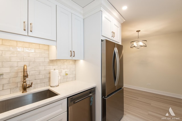 kitchen with a sink, decorative backsplash, light countertops, white cabinets, and stainless steel appliances