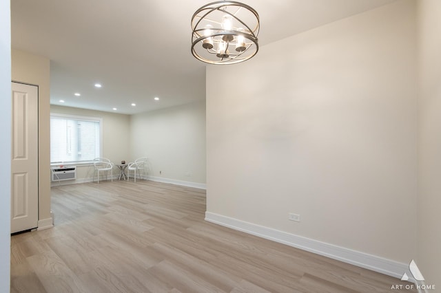 empty room with an AC wall unit, recessed lighting, light wood-style floors, baseboards, and a chandelier