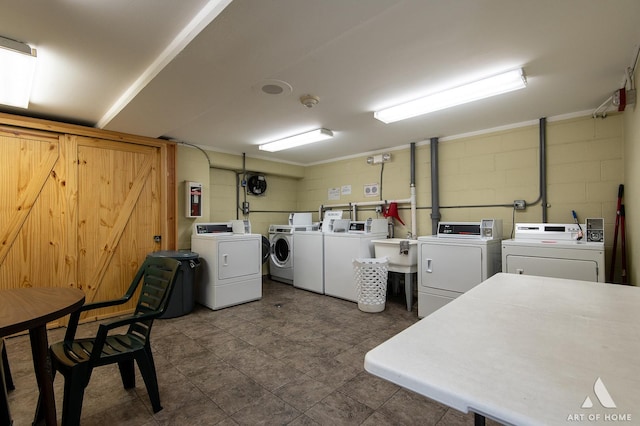 common laundry area featuring a sink, a barn door, independent washer and dryer, and concrete block wall