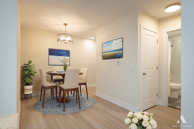 dining room with baseboards, a notable chandelier, and light wood finished floors