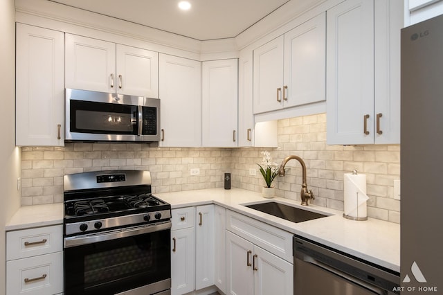 kitchen featuring appliances with stainless steel finishes, white cabinetry, light countertops, and a sink