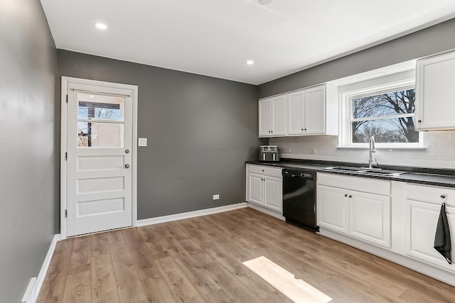 kitchen with dark countertops, dishwasher, light wood-type flooring, and a sink