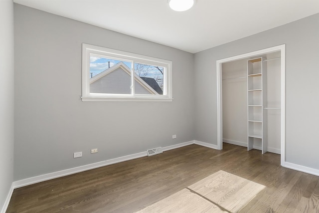 unfurnished bedroom with a closet, visible vents, baseboards, and dark wood-style flooring