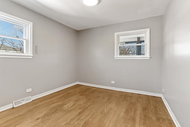 unfurnished room featuring visible vents, baseboards, and wood finished floors