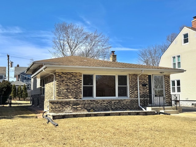 view of front of property with brick siding, a chimney, a front lawn, and fence