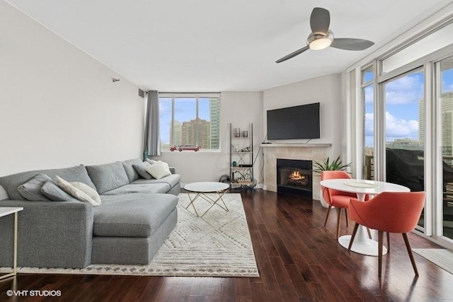 living room featuring ceiling fan, wood finished floors, and a lit fireplace