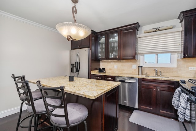 kitchen with a breakfast bar, a sink, backsplash, stainless steel appliances, and crown molding