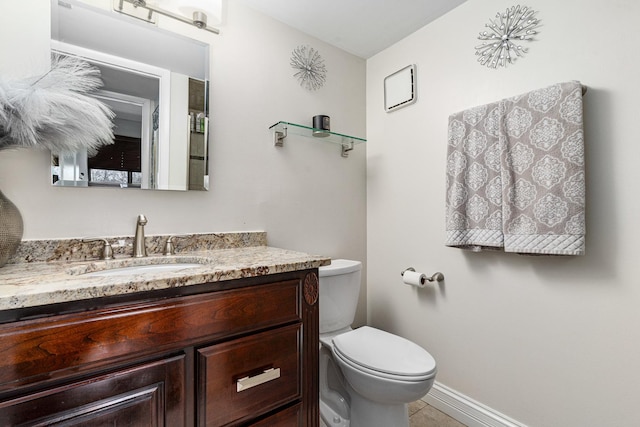 half bathroom featuring vanity, tile patterned floors, toilet, and baseboards