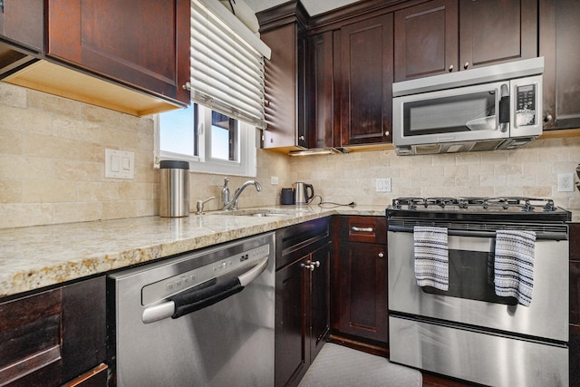 kitchen featuring tasteful backsplash, appliances with stainless steel finishes, light stone counters, and a sink