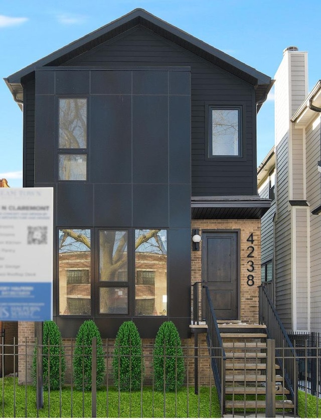 view of front of home with a fenced front yard and brick siding