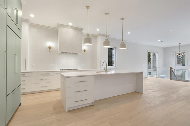 kitchen featuring light countertops, a center island with sink, light wood-type flooring, and a sink