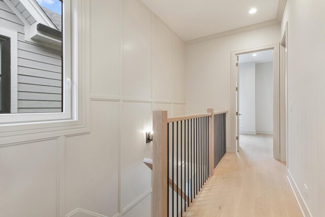 stairway with a decorative wall, wood finished floors, visible vents, and baseboards