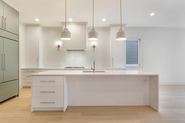 kitchen with light wood finished floors, stainless steel gas cooktop, paneled built in fridge, a sink, and light countertops