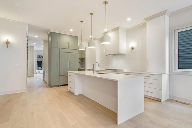 kitchen with light wood finished floors, visible vents, stainless steel gas cooktop, light countertops, and a sink