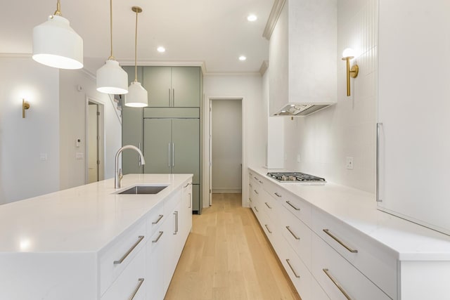 kitchen with premium range hood, a large island with sink, a sink, stainless steel gas stovetop, and light wood-type flooring