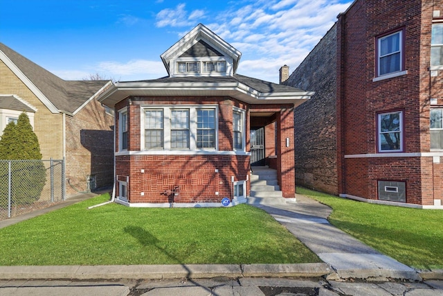 view of front of house featuring brick siding, a front lawn, and fence