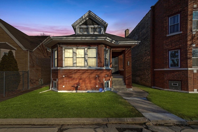 view of front of home with a front lawn, fence, and brick siding