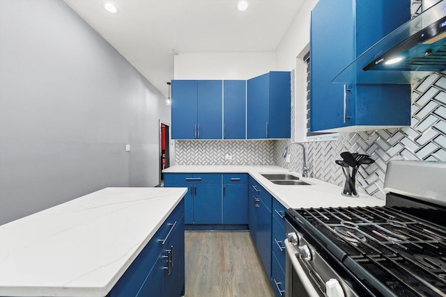 kitchen with stainless steel gas stove, light wood-type flooring, blue cabinets, and a sink