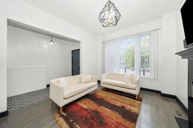 living room with a notable chandelier, a fireplace, baseboards, and wood finished floors