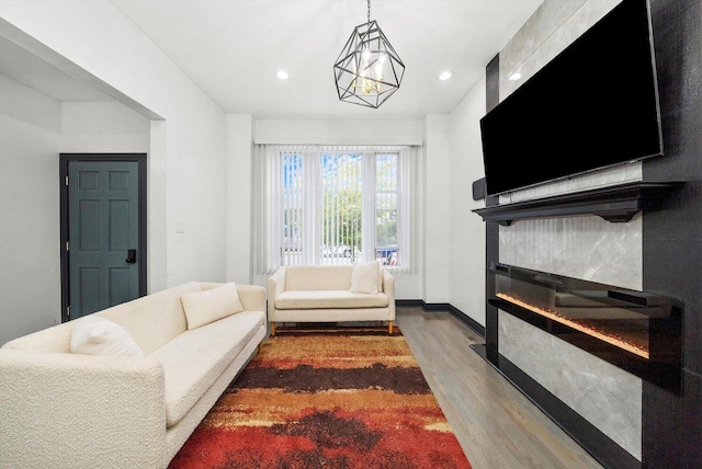 living room featuring a glass covered fireplace, recessed lighting, wood finished floors, and baseboards