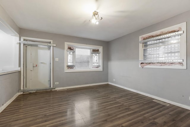 unfurnished room with baseboards and dark wood-style flooring