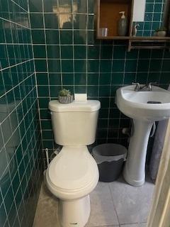bathroom featuring toilet, tile walls, and tile patterned flooring