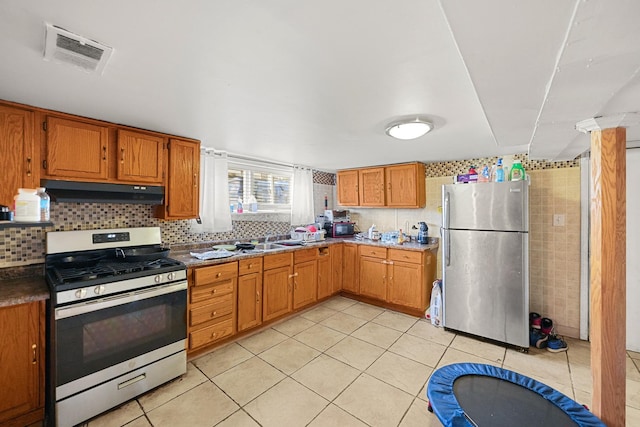 kitchen with under cabinet range hood, visible vents, appliances with stainless steel finishes, and light tile patterned floors