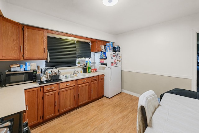 kitchen with stainless steel microwave, light countertops, freestanding refrigerator, and a sink