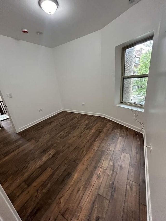 unfurnished room featuring baseboards and dark wood-style flooring