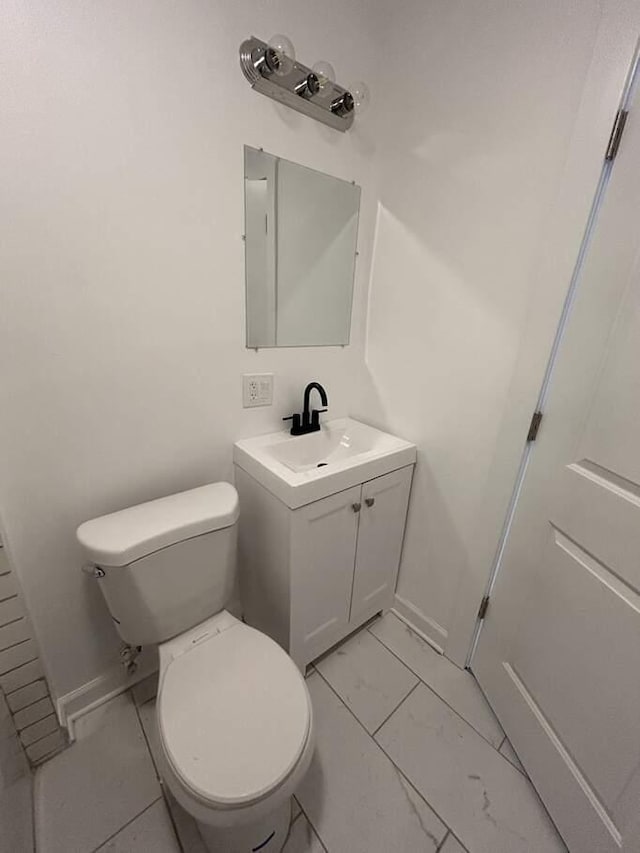 bathroom with marble finish floor, toilet, and vanity