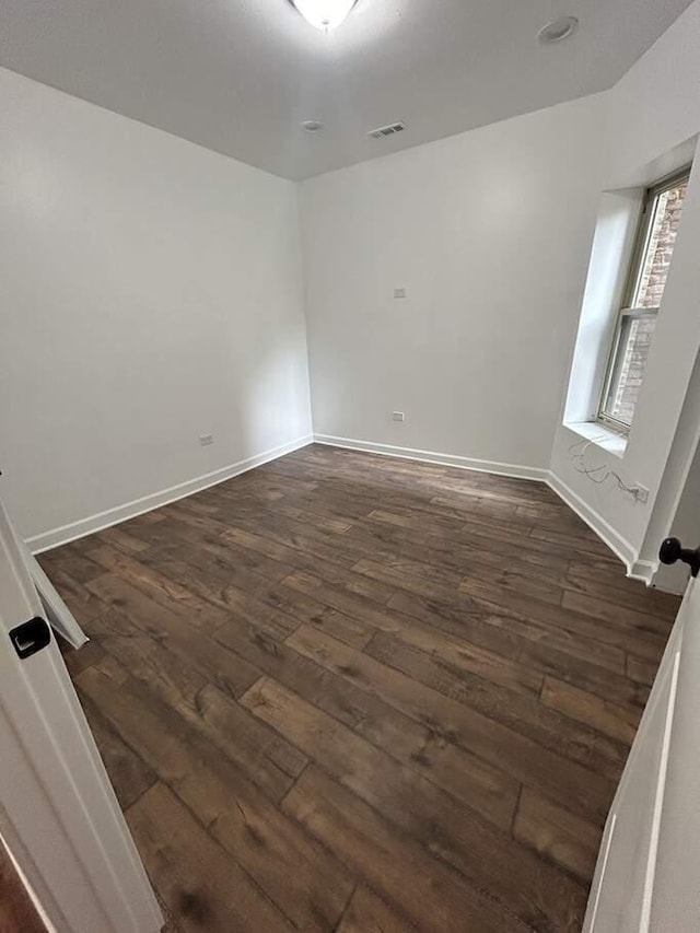 unfurnished room with dark wood-type flooring, baseboards, and visible vents