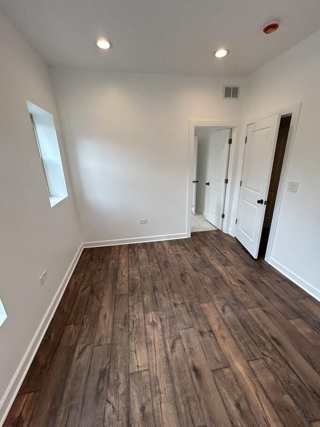 spare room featuring visible vents, baseboards, and dark wood-style floors