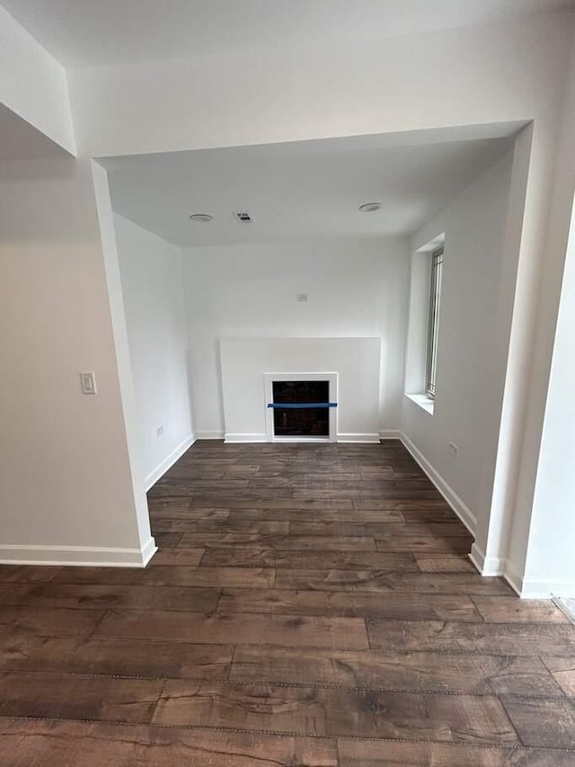 unfurnished living room featuring wood finished floors, a fireplace, baseboards, and visible vents