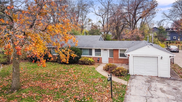 ranch-style house with brick siding, a front lawn, roof with shingles, a garage, and driveway