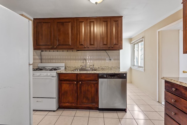 kitchen featuring white appliances, light tile patterned floors, light stone countertops, a sink, and tasteful backsplash