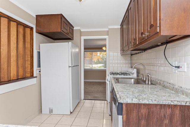 kitchen with a sink, backsplash, freestanding refrigerator, crown molding, and light countertops