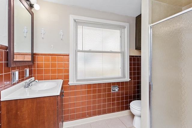 bathroom with tile patterned floors, toilet, a stall shower, tile walls, and vanity