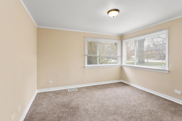 empty room with visible vents, carpet, baseboards, and ornamental molding