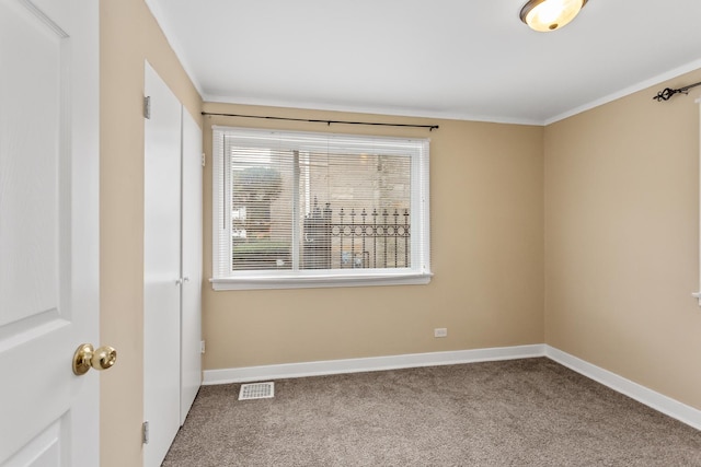 carpeted spare room featuring baseboards, visible vents, and ornamental molding