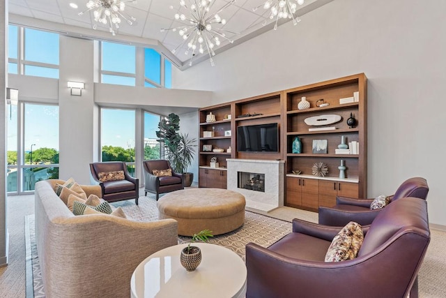 living area with an inviting chandelier, a high ceiling, and a premium fireplace