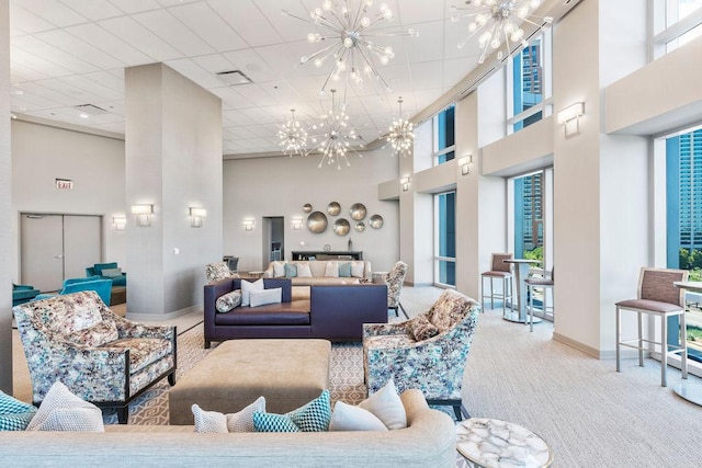 living room with a towering ceiling, an inviting chandelier, and carpet floors