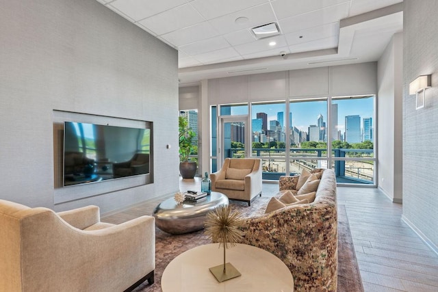 living room with a drop ceiling, baseboards, hardwood / wood-style floors, and a towering ceiling